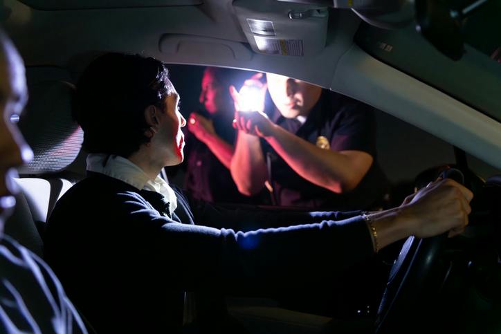 Police officer shining light onto man in car