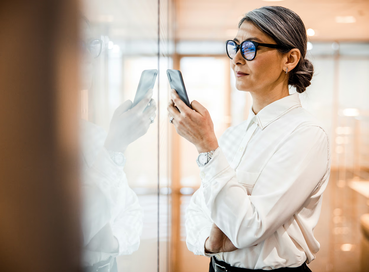 Managerin analysiert Recruiting KPI auf dem Smartphone und überprüft HR-Analytics-Daten zur Performance im Bewerbungsprozess.