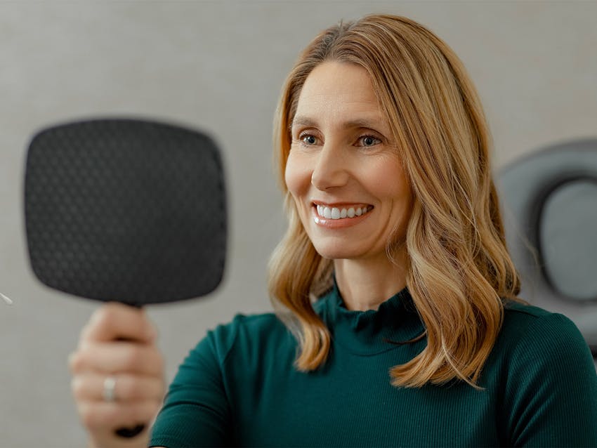 woman looking into a hand mirror