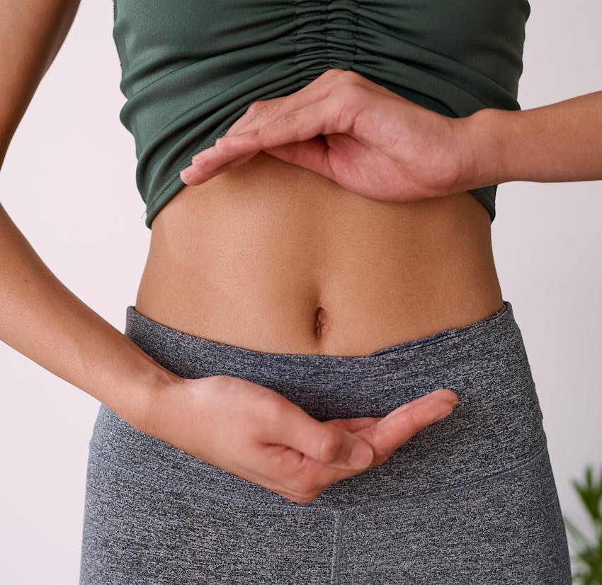 womans stomach with hands around