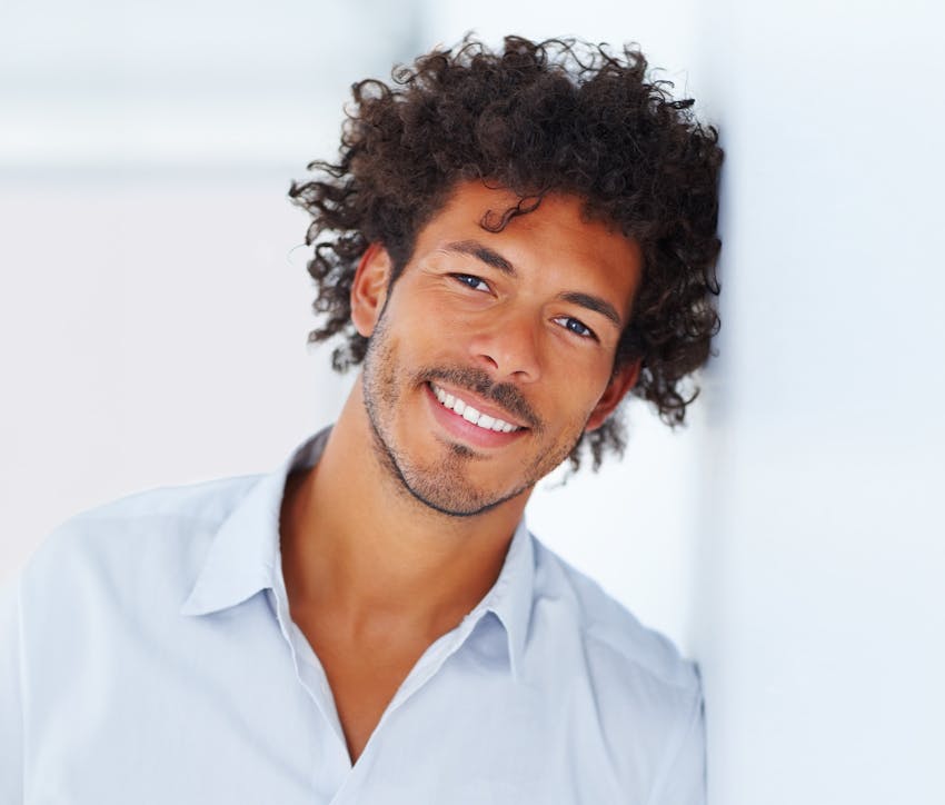man smiling leaning against wall