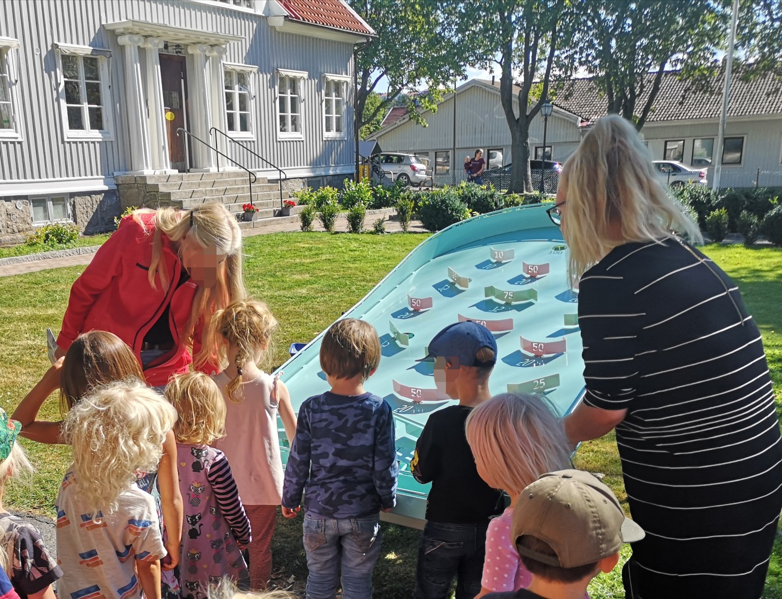 Barn och vuxna runt ett Pinpoint på en gräsmatta
