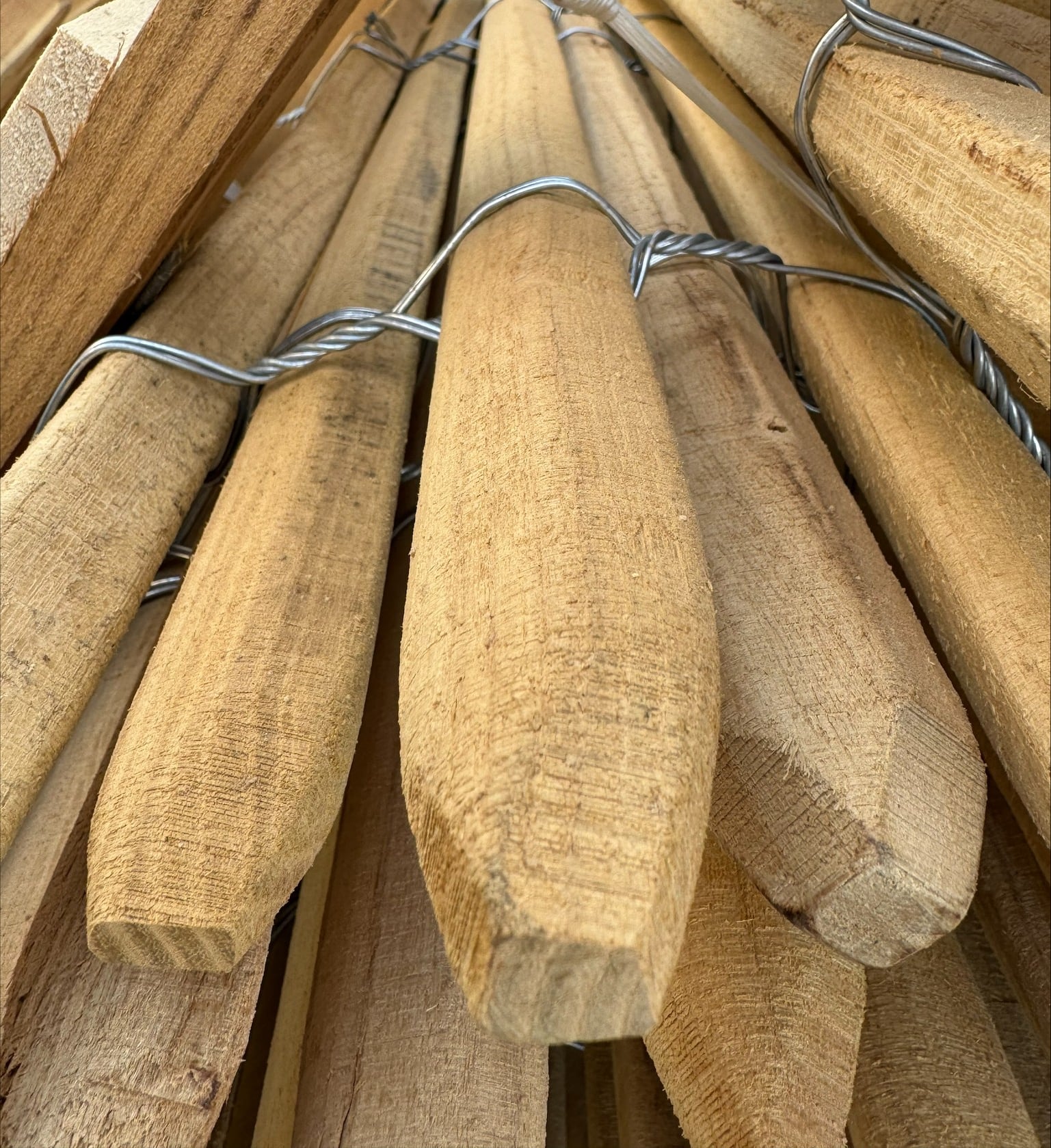 Närbild på sågade och spetsade spjälor i robinia, sammanfogade med tvinnad ståltråd till ett rullstaket