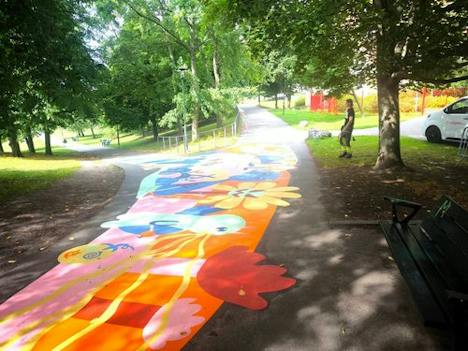 Målat stråk med blommor och figurer genom en park