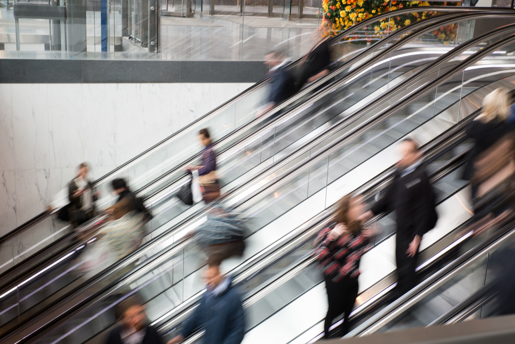 Blurred image of a bunch of people on a escalator in motion.