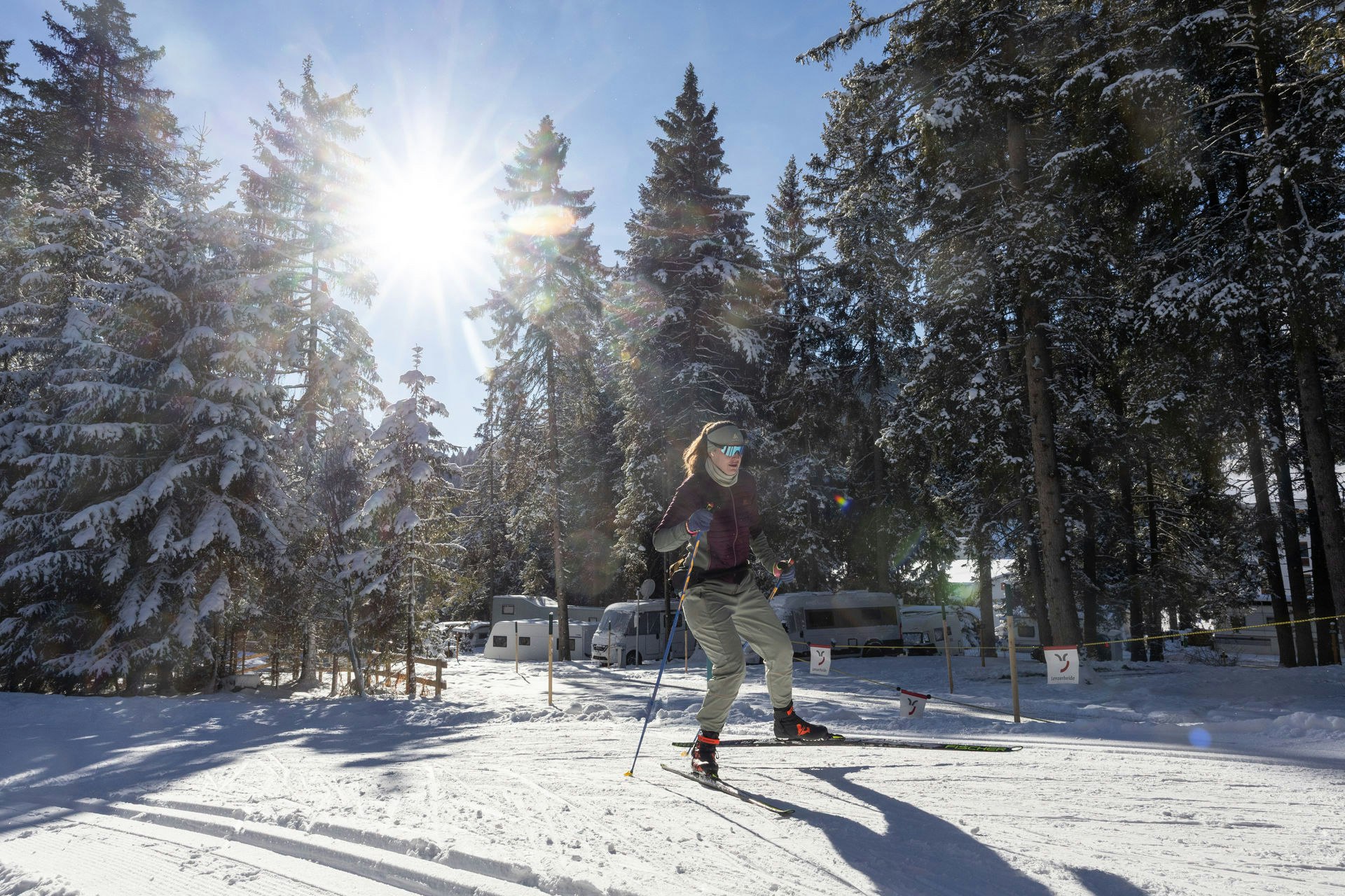 Langlaufen beim Camping Gravas Winterlicher Campingplatz mit Sonne und Langläuferin