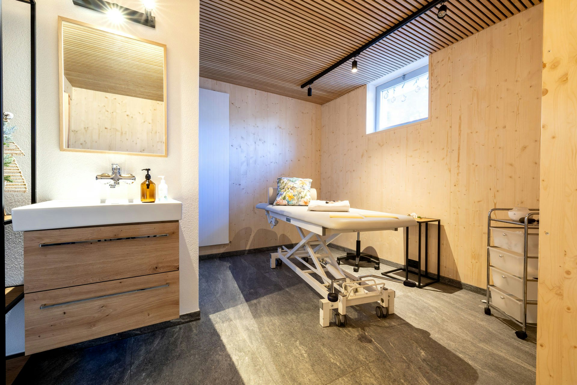 Waschbecken und Massagebett im Raum mit Holzverkleidung