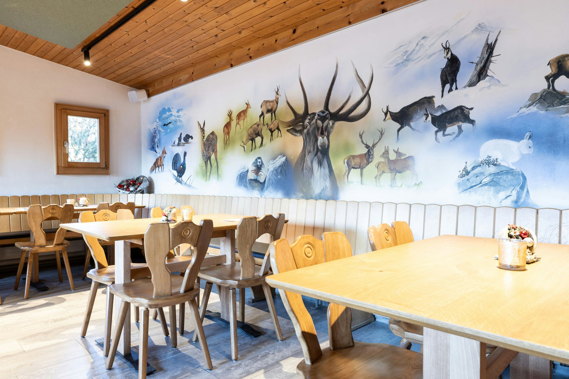 Tische unter Wandbild mit Wildtieren im Restaurant
