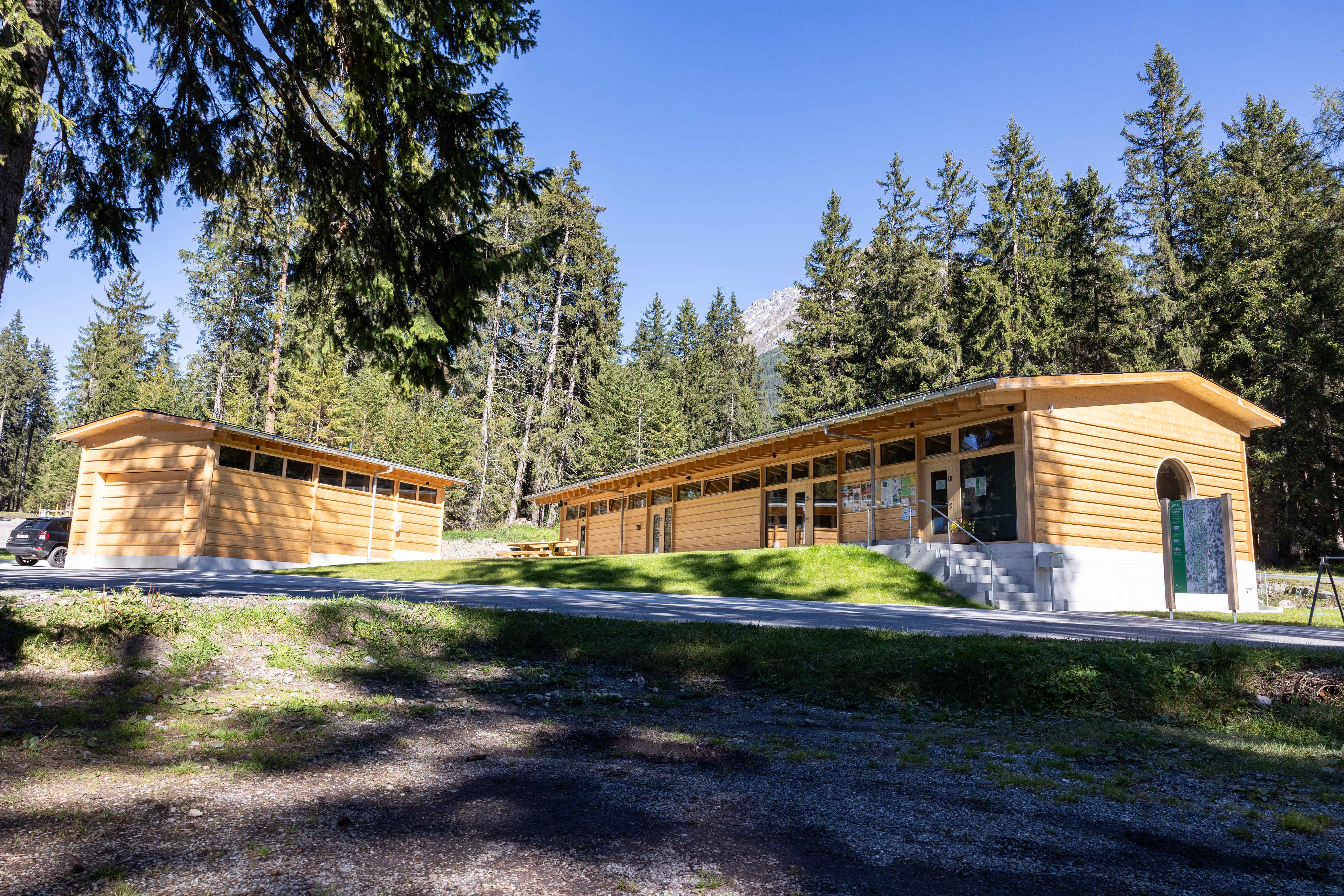 Holzgebäude mit Zufahrtsweg im Sonnenlicht, Camping Gravas