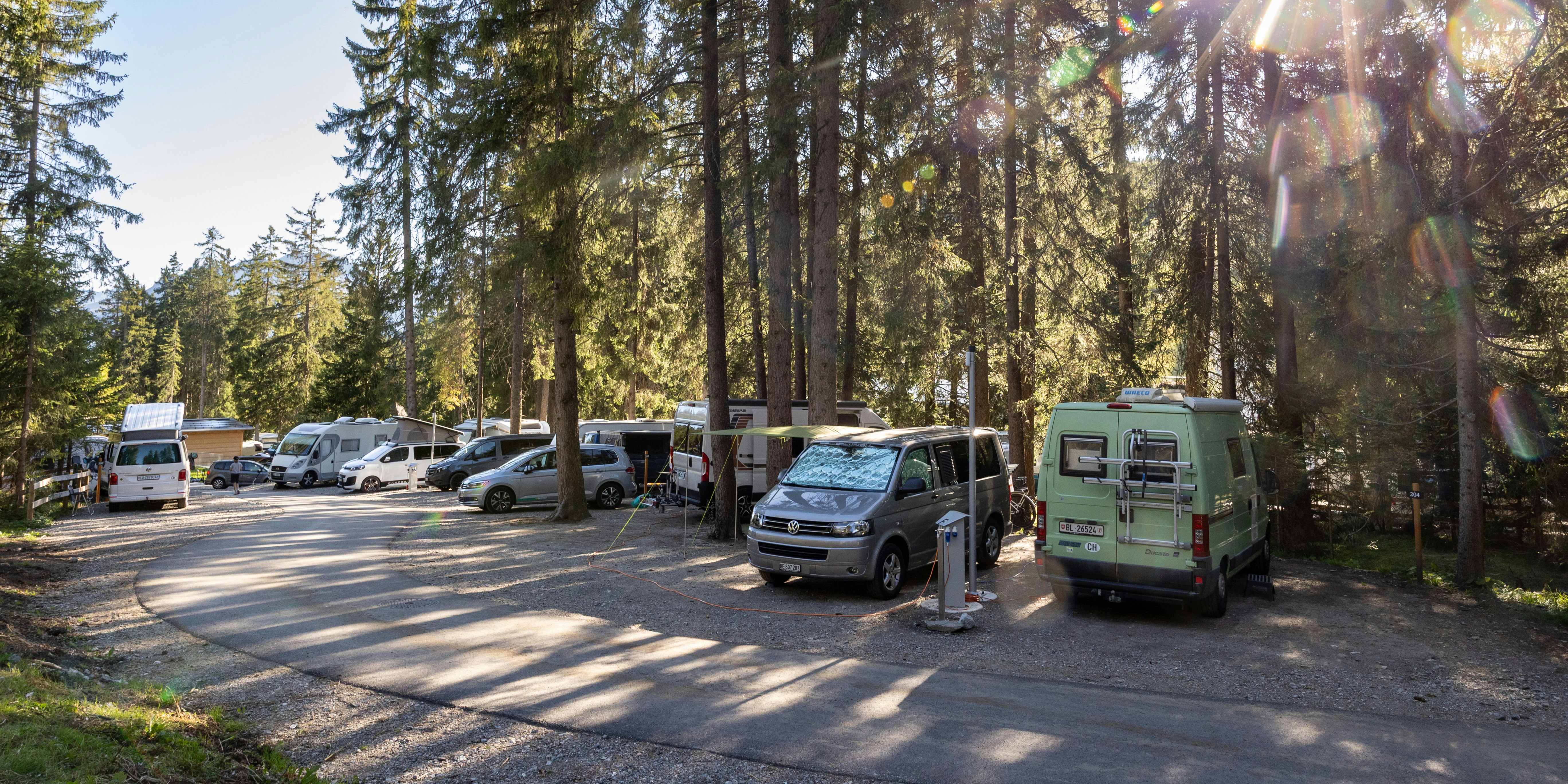 Sonniger Stellplatz im Wald Wohnmobile auf Stellplatz mit Sonnenlicht durch die Bäume, Camping Gravas