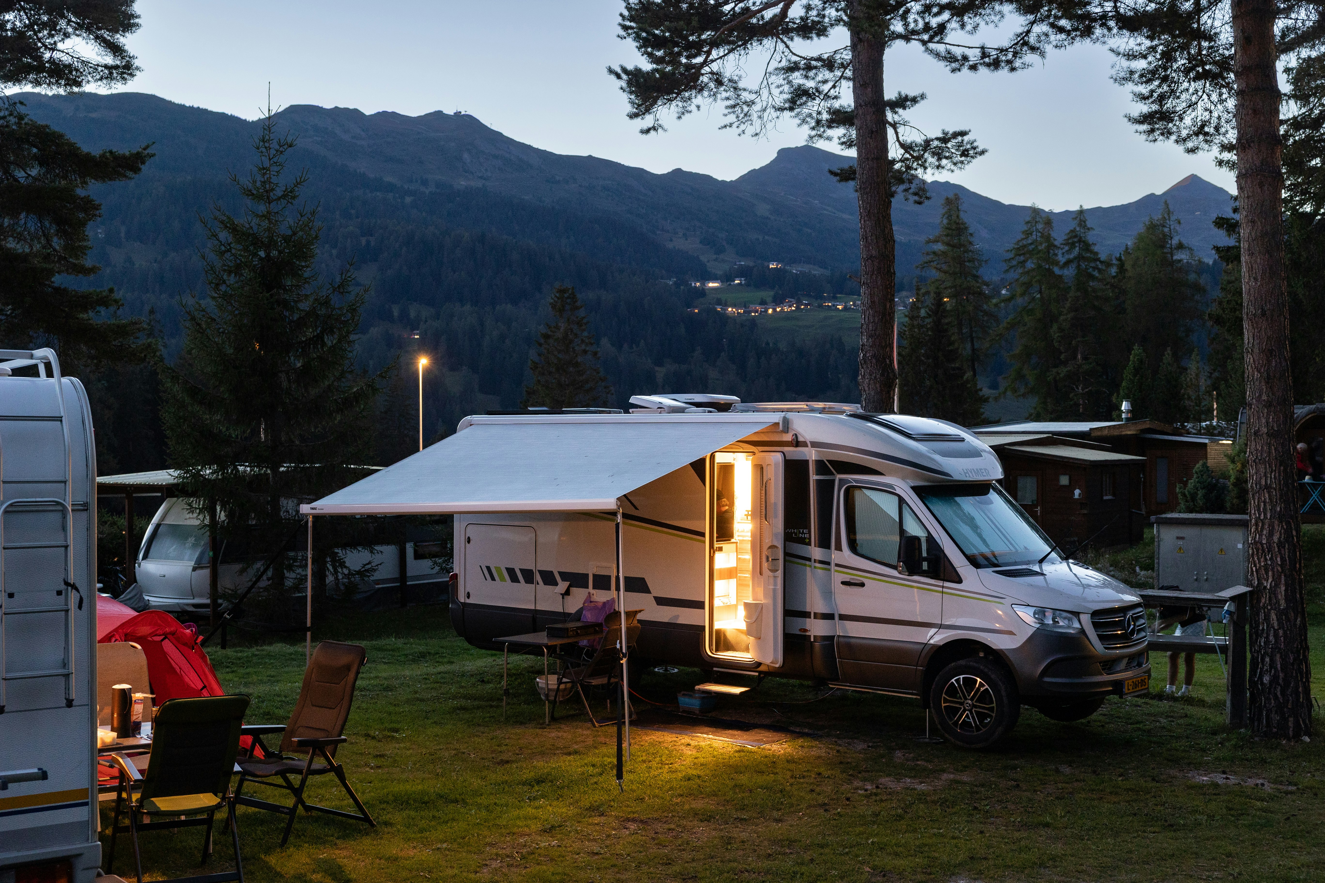 Wohnmobile zwischen Bäumen im warmen Abendlicht, Camping St. Cassian
