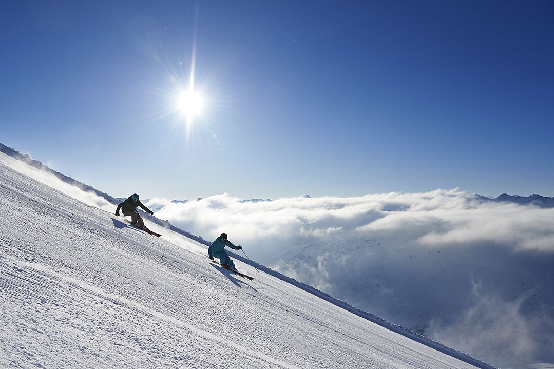 Skifahrer bei der Abfahrt vor strahlend blauem Himmel