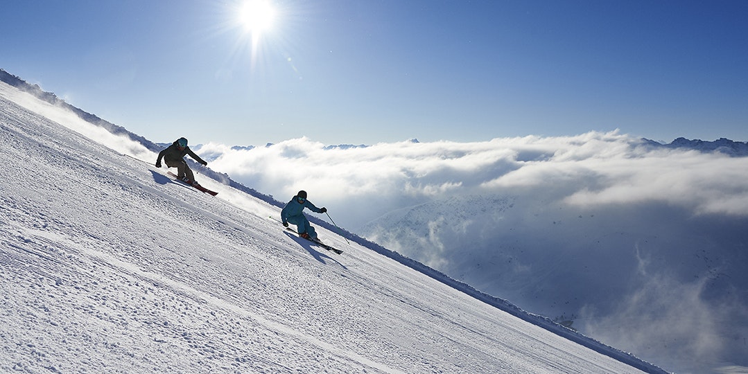 Skifahren in Lenzerheide Skifahrer bei der Abfahrt vor strahlend blauem Himmel