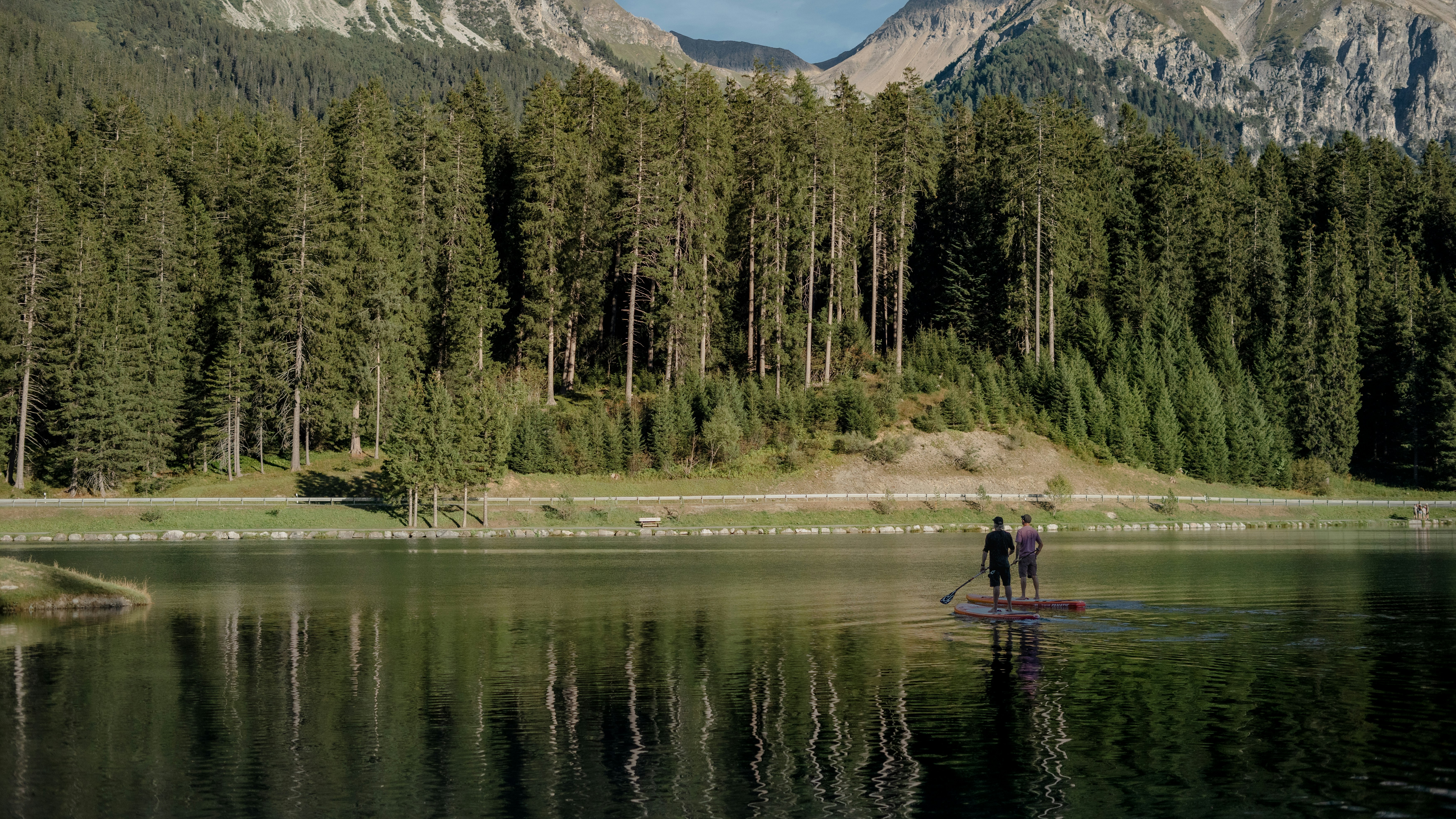 Aktivitäten rund um Lenzerheide Bergsee mit Bergpanorama im Hintergrund und zwei Leute auf dem SUP