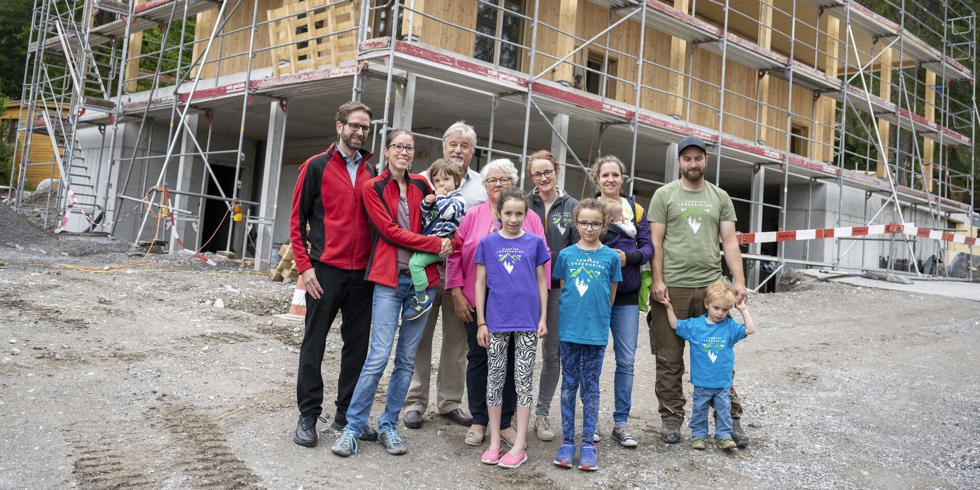 Familie Nadig Gruppe von Erwachsenen und Kindern vor dem im Bau befindlichen Gebäude