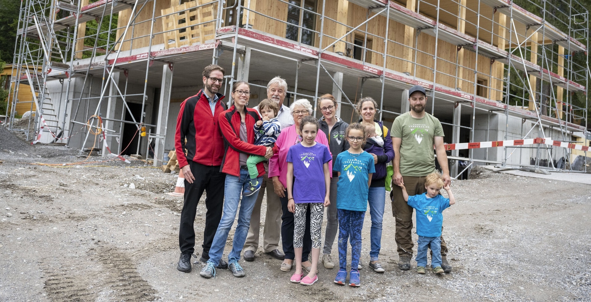 Gruppe von Erwachsenen und Kindern vor dem im Bau befindlichen Gebäude