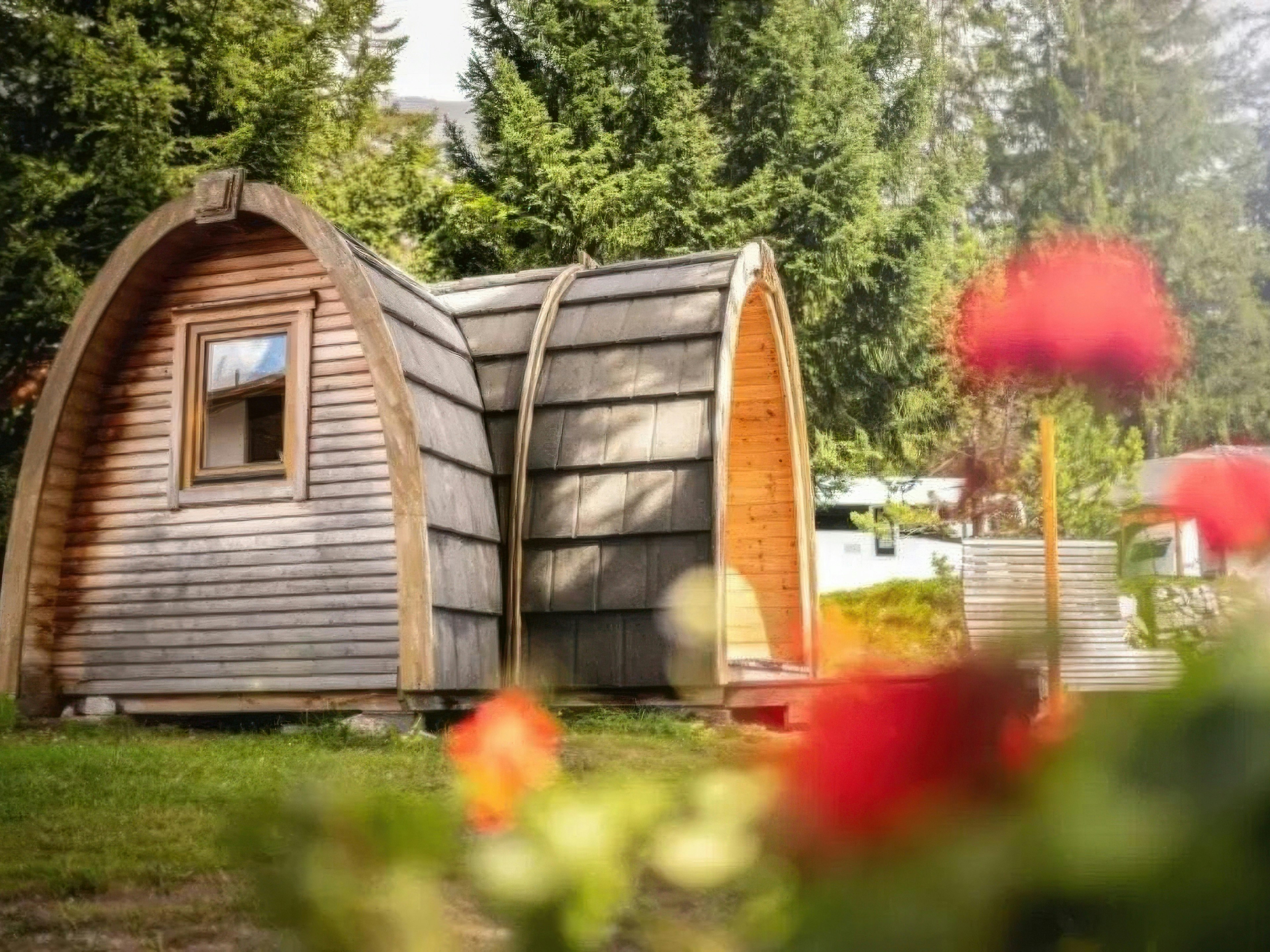 Camping St. Cassian Holziglu Rustikale Camping-Pod-Hütte umgeben von blühenden Blumen im Sommer