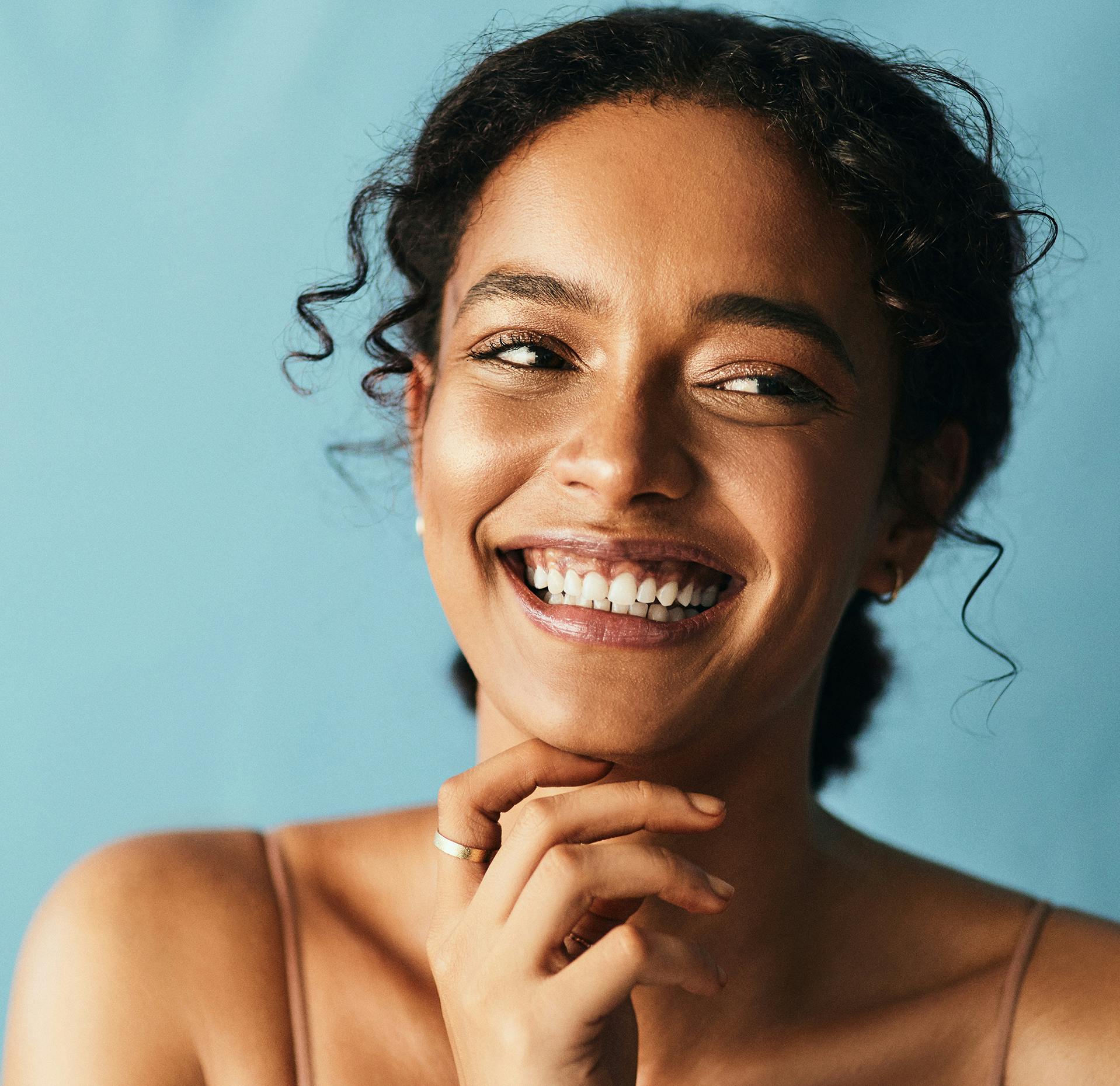 close up of a smiling woman with hand on chin