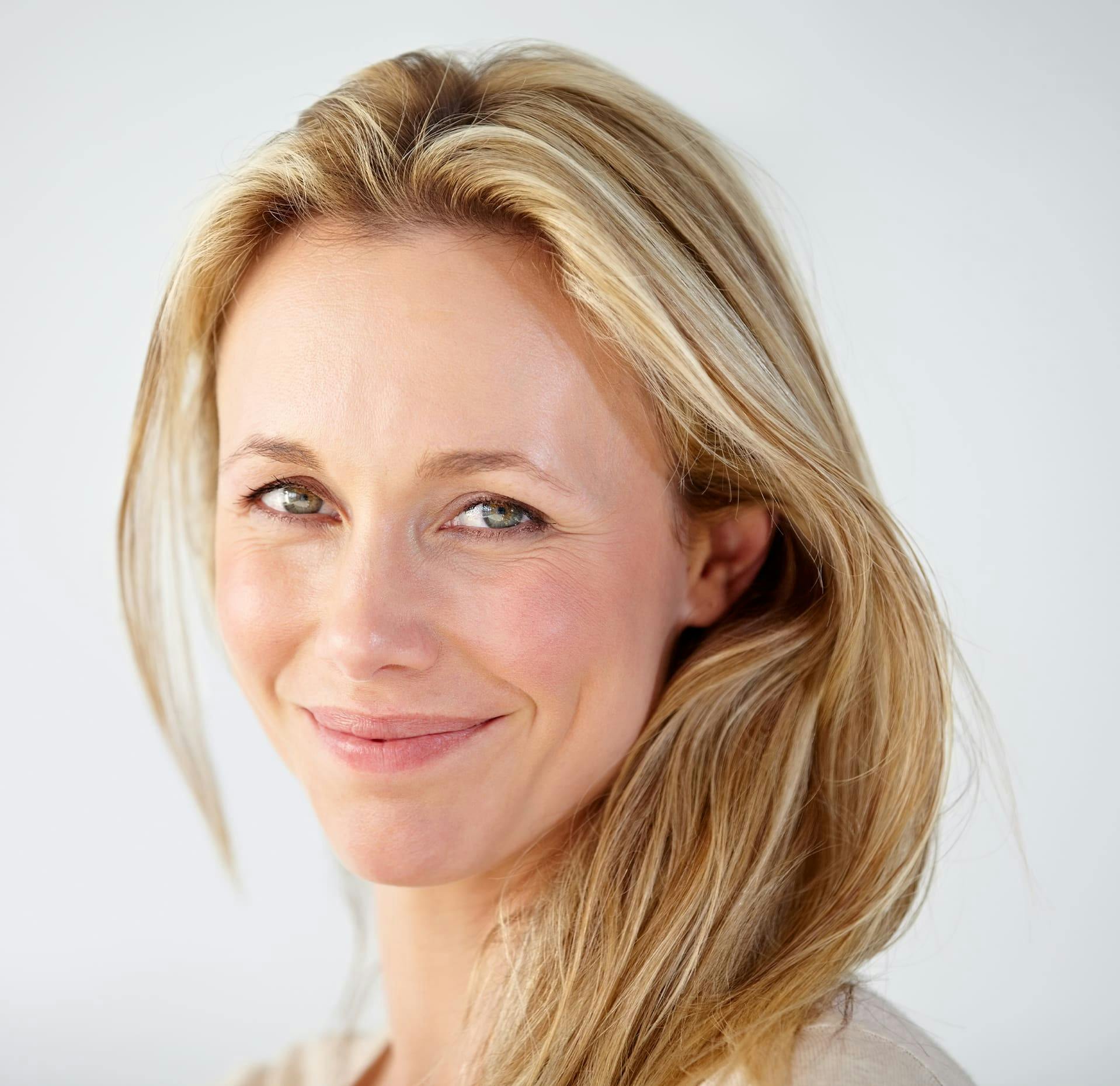close up of a blond woman with long hair smiling at the camera