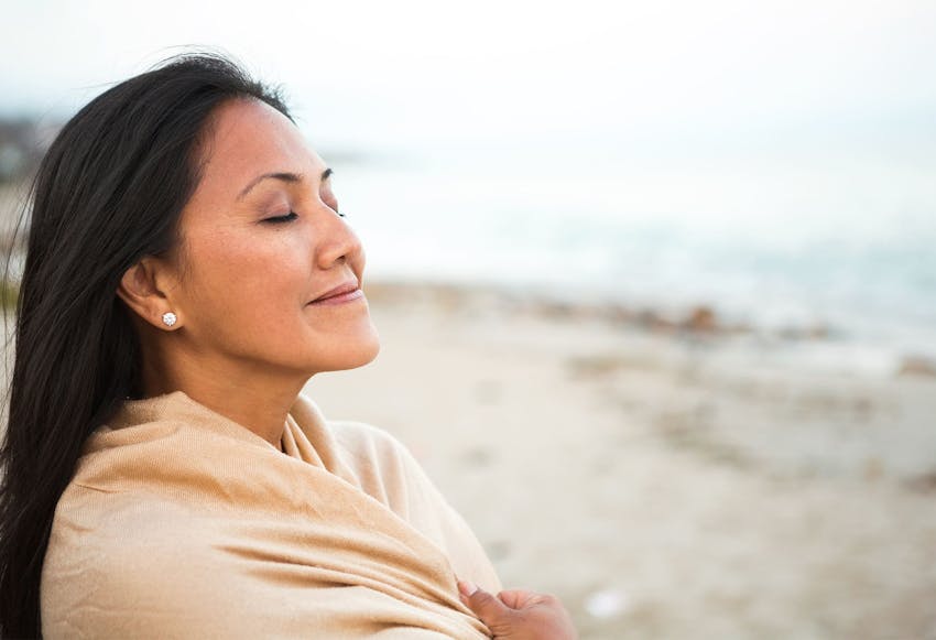 Woman wrapped in a blanket on the beach