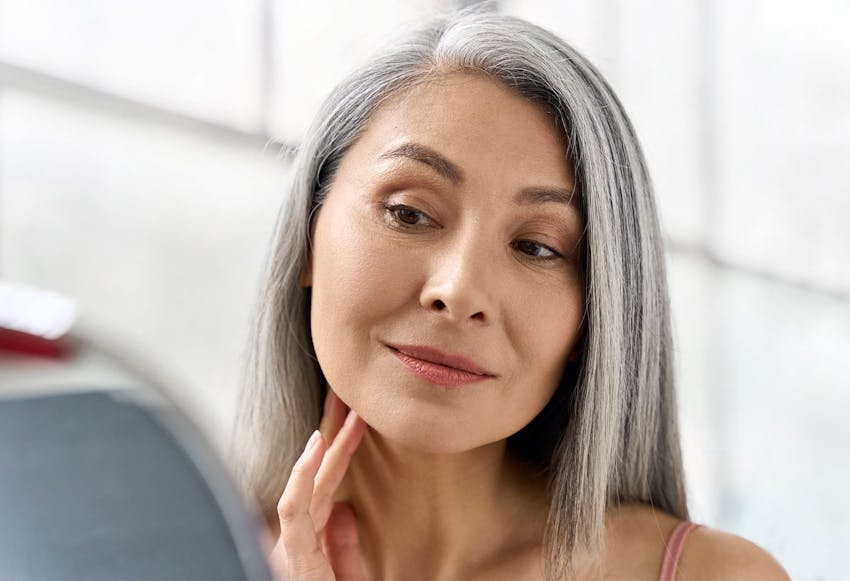 Woman with gray hair looking in the mirror