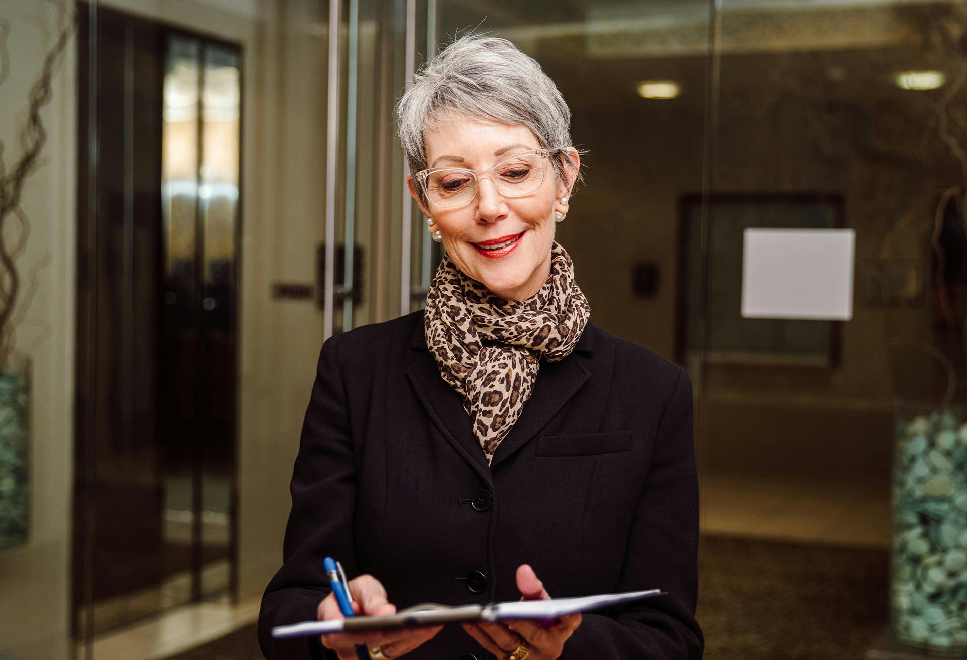A woman with glasses looking at a clipboard