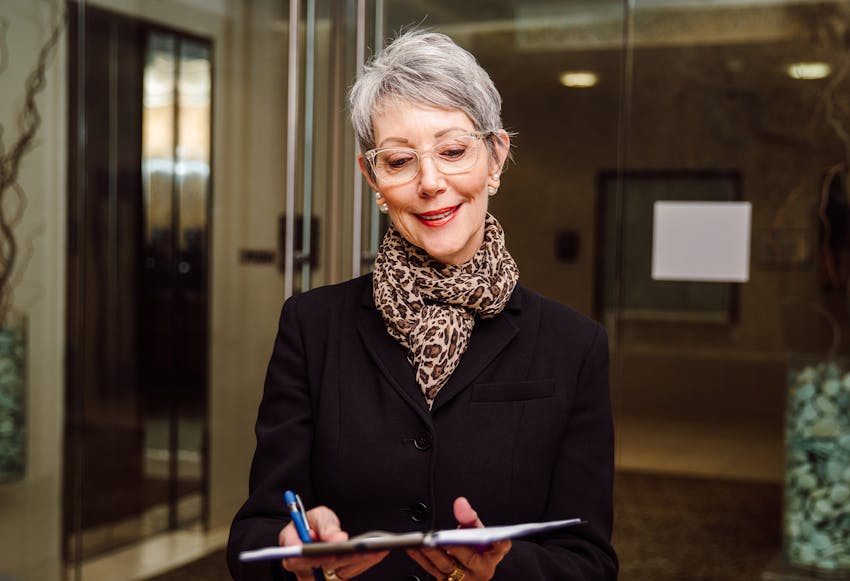 A woman with glasses looking at a clipboard