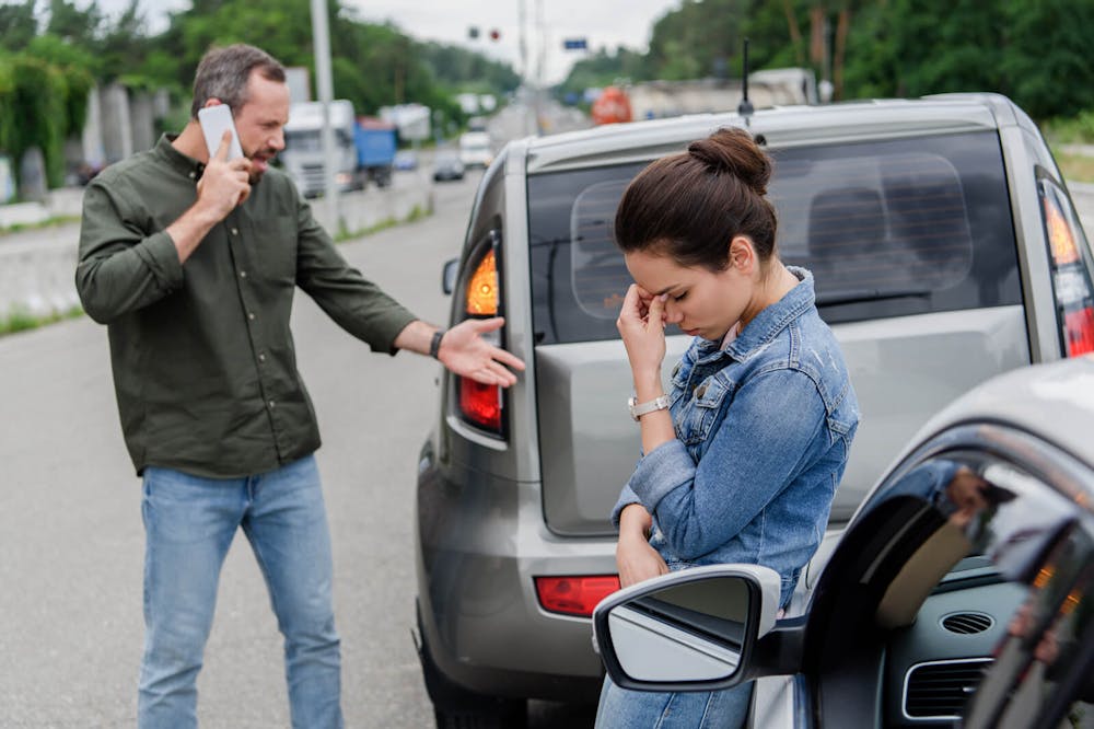 Car accident Upset man and woman near cars after car accident. This image answers the question why you need a car accident lawyer.