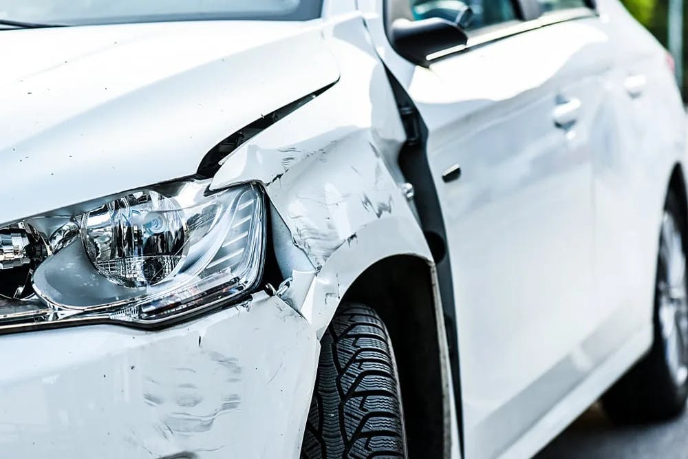 Damaged white car after a hit and run accident