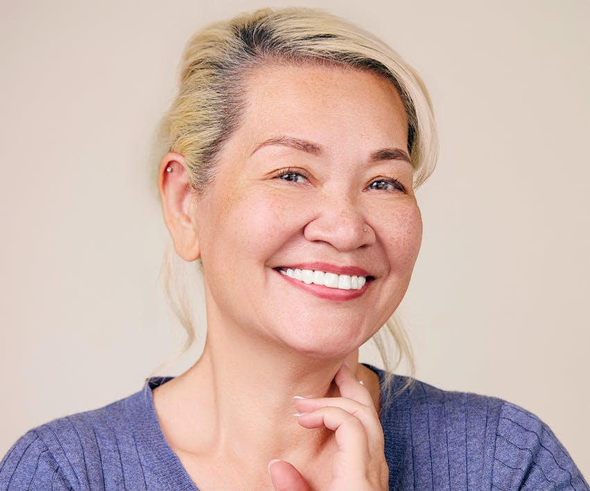 woman smiling touching neck