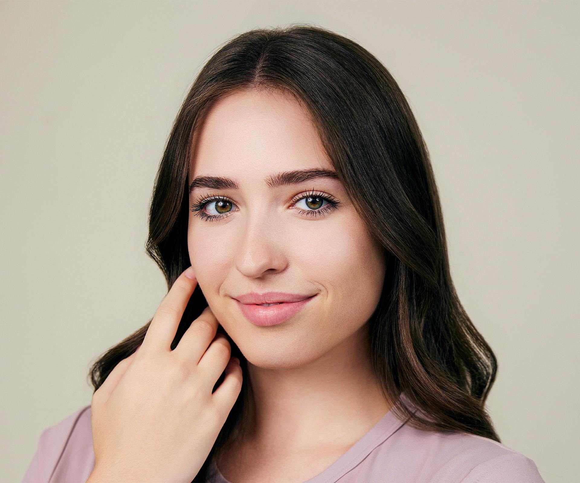 woman with soft smile touching face