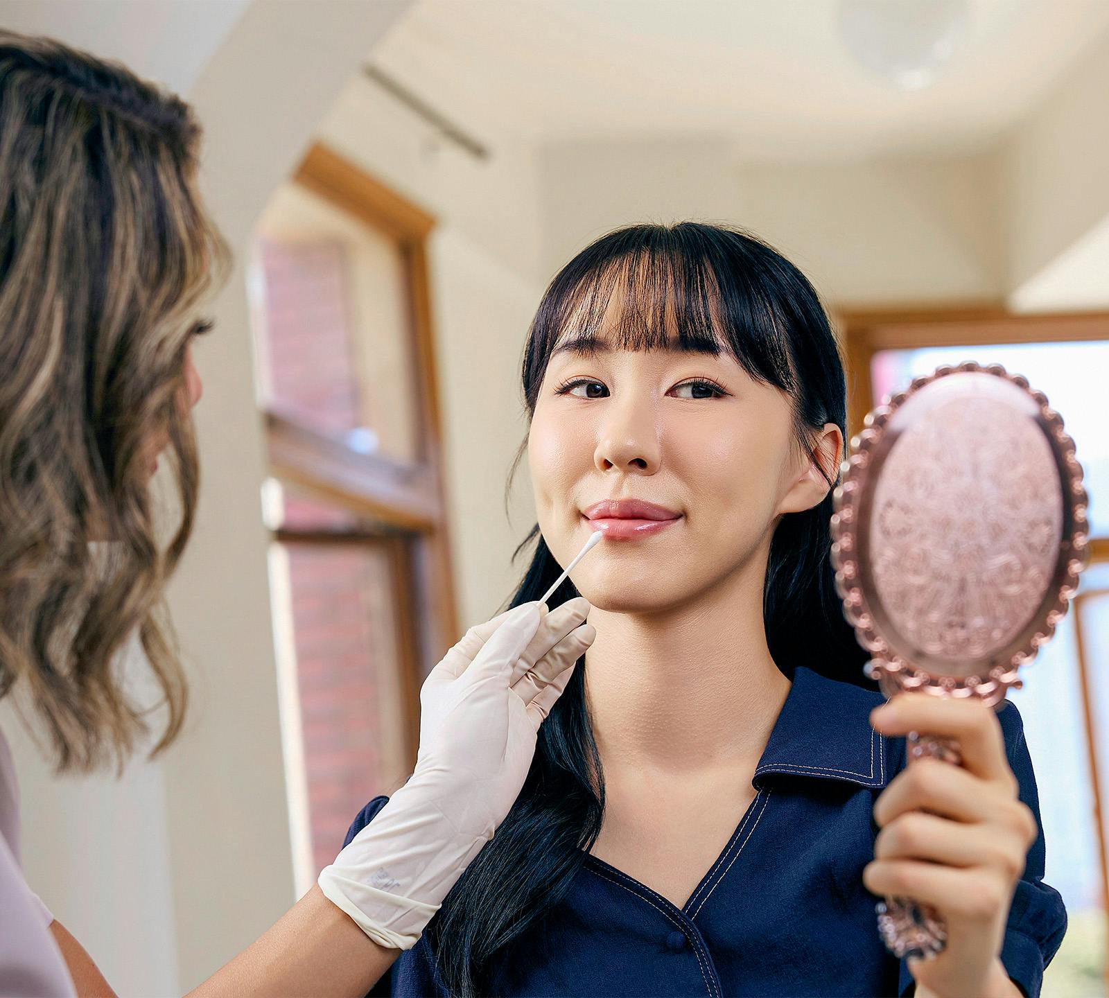 woman looking over in hand held mirror