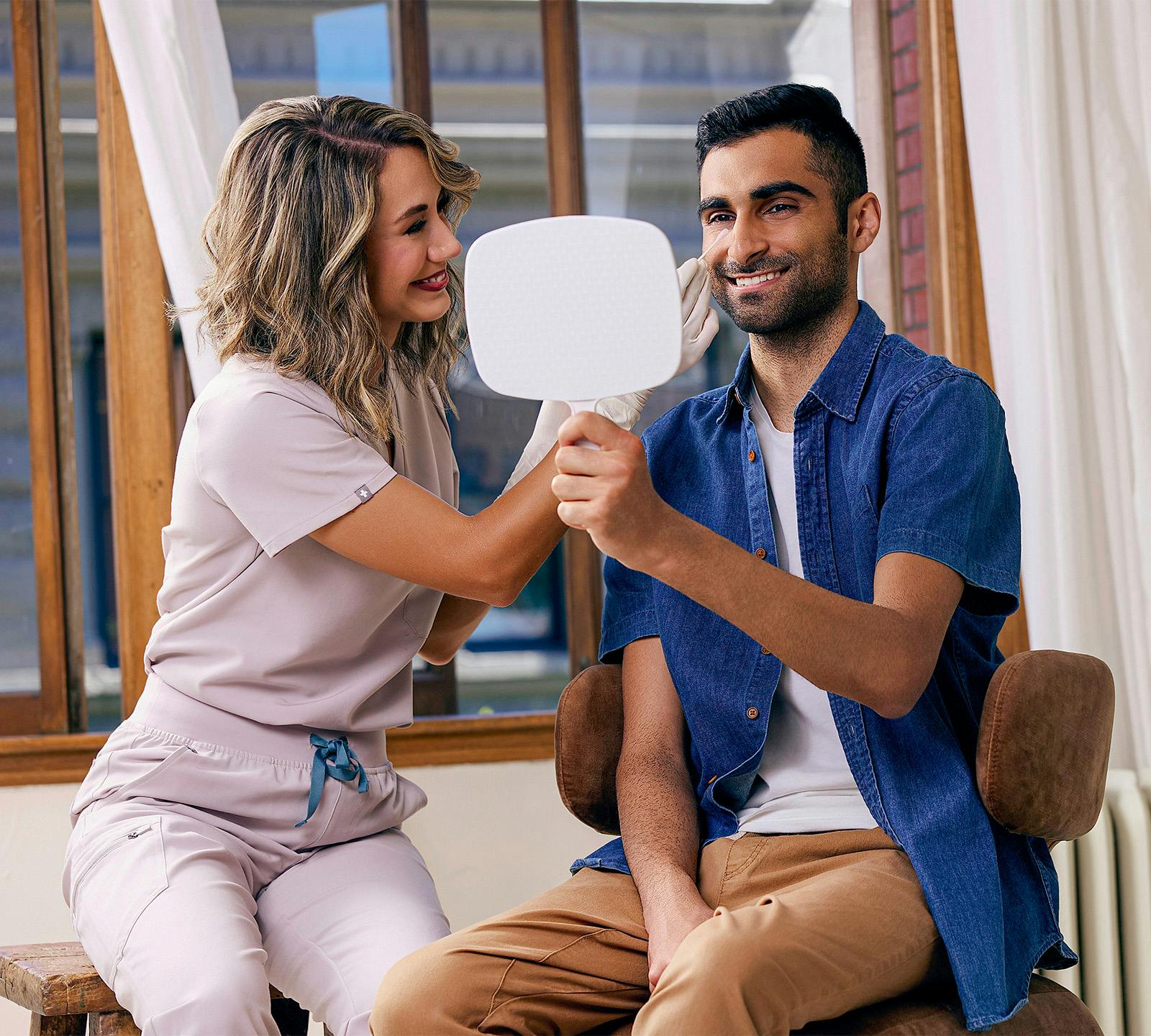 man looking in hand held mirror smiling
