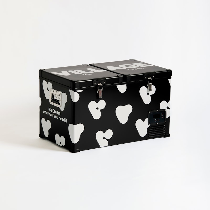 A black portable freezer with white cow-like spots and the text ice cream wherever you need it printed on the side, placed against a plain white background.