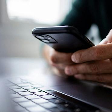 person holding phone over keyboard
