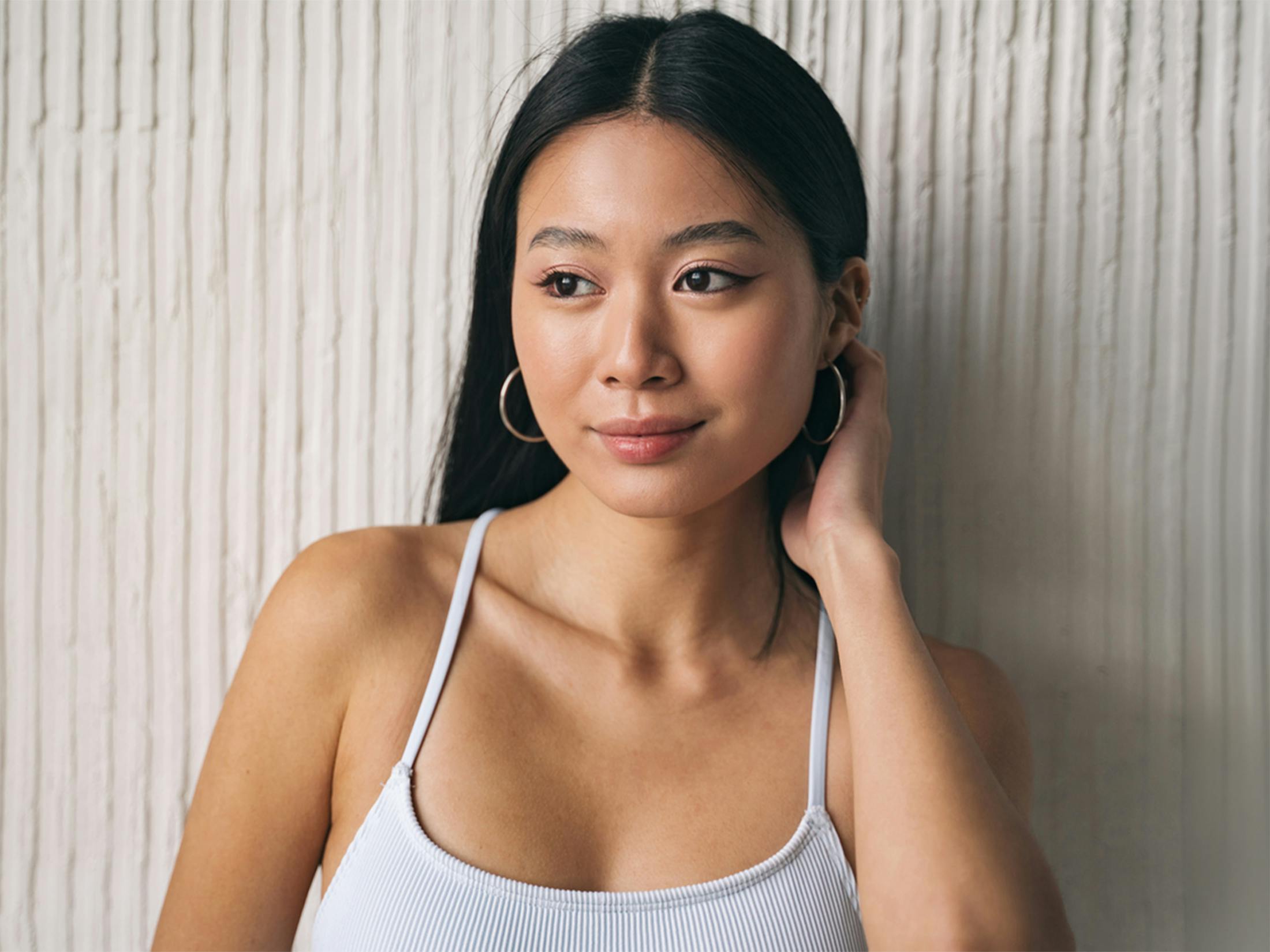 woman with a soft smile touching her hair