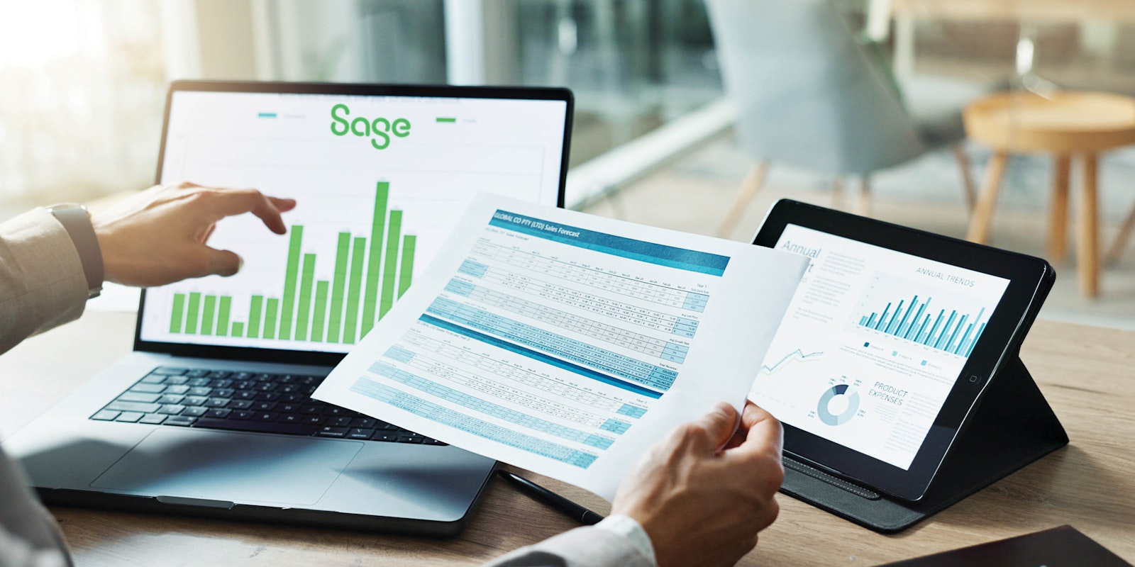 Laptop displaying Sage Intacct software beside financial reports with upward-trending graphs representing improved business performance through integrations