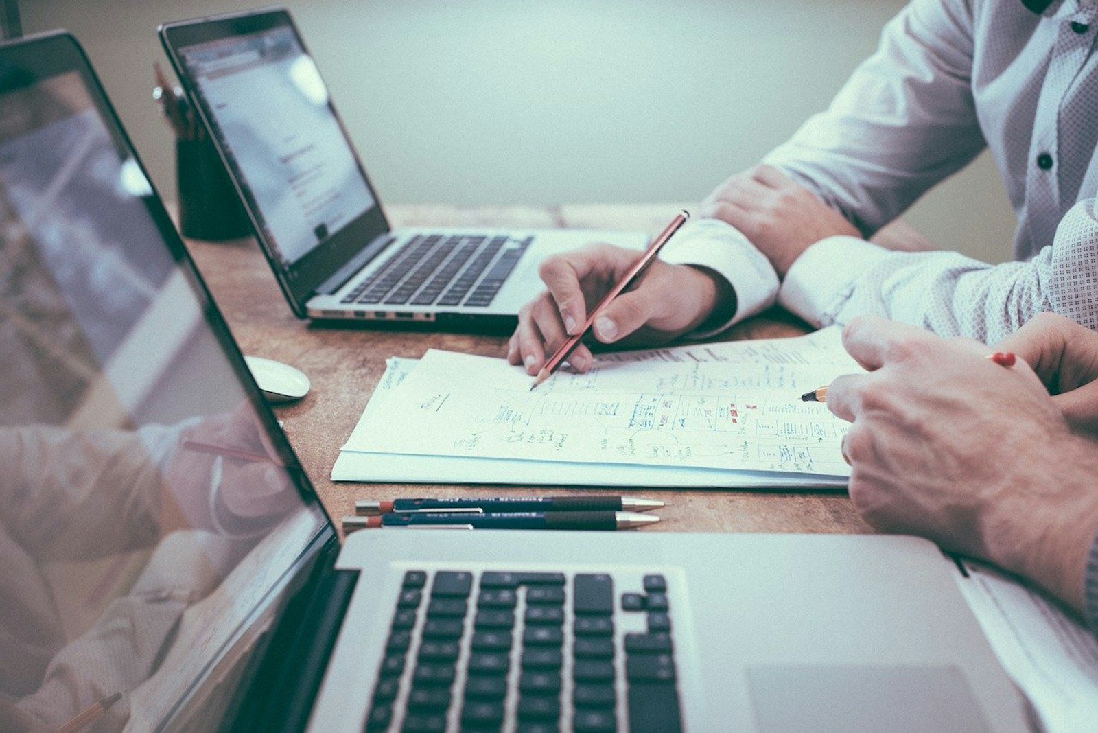 Graphic featuring two professionals reviewing documents and working on laptops, symbolizing efficient order management and workflow optimization.