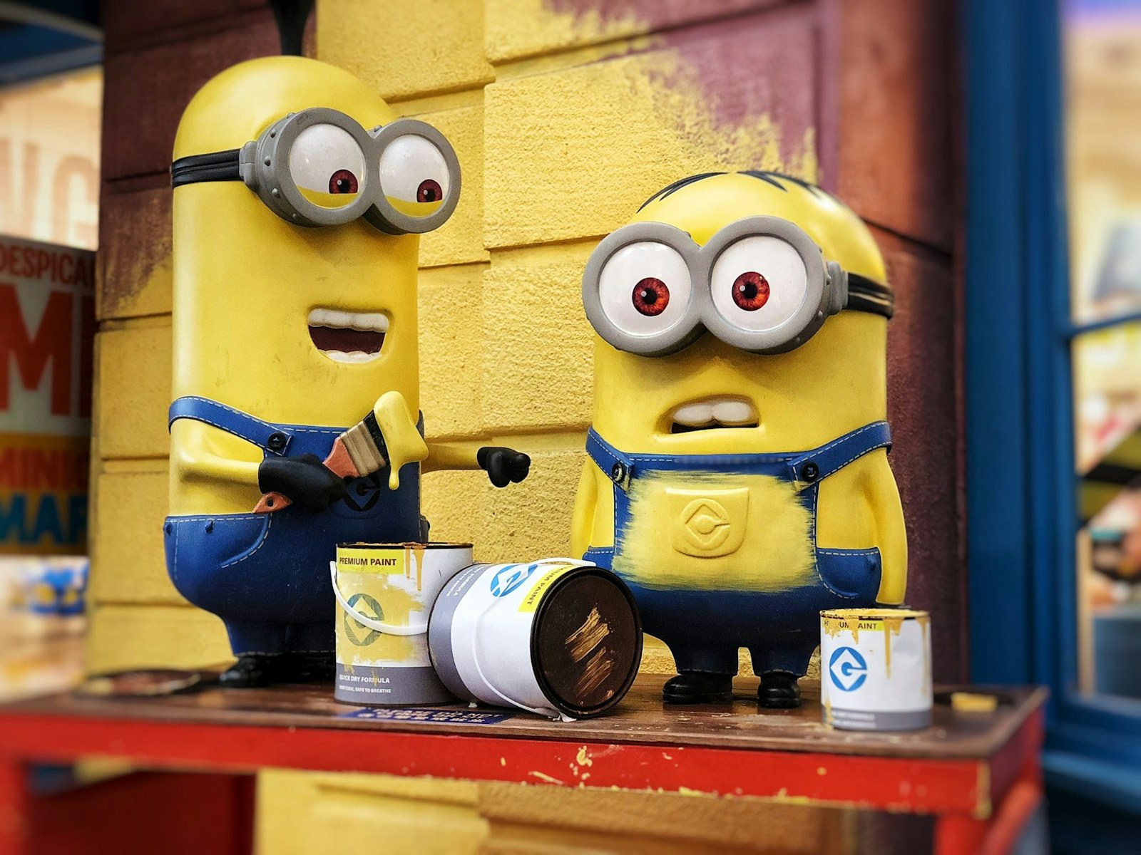 Cartoon illustration of one Minion accidentally painting another’s overalls, symbolizing business errors, unexpected issues, and ecommerce challenges.