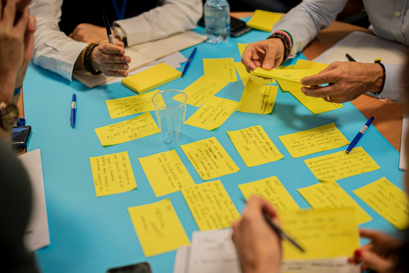 Graphic showing a team organizing yellow index cards around a table, symbolizing webhooks, automated workflows, and process coordination.