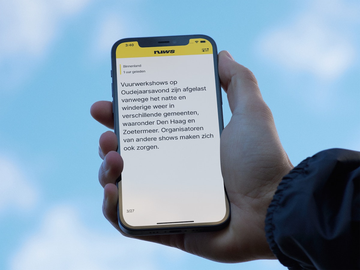 A person holding an iPhone with the Nuws app opened