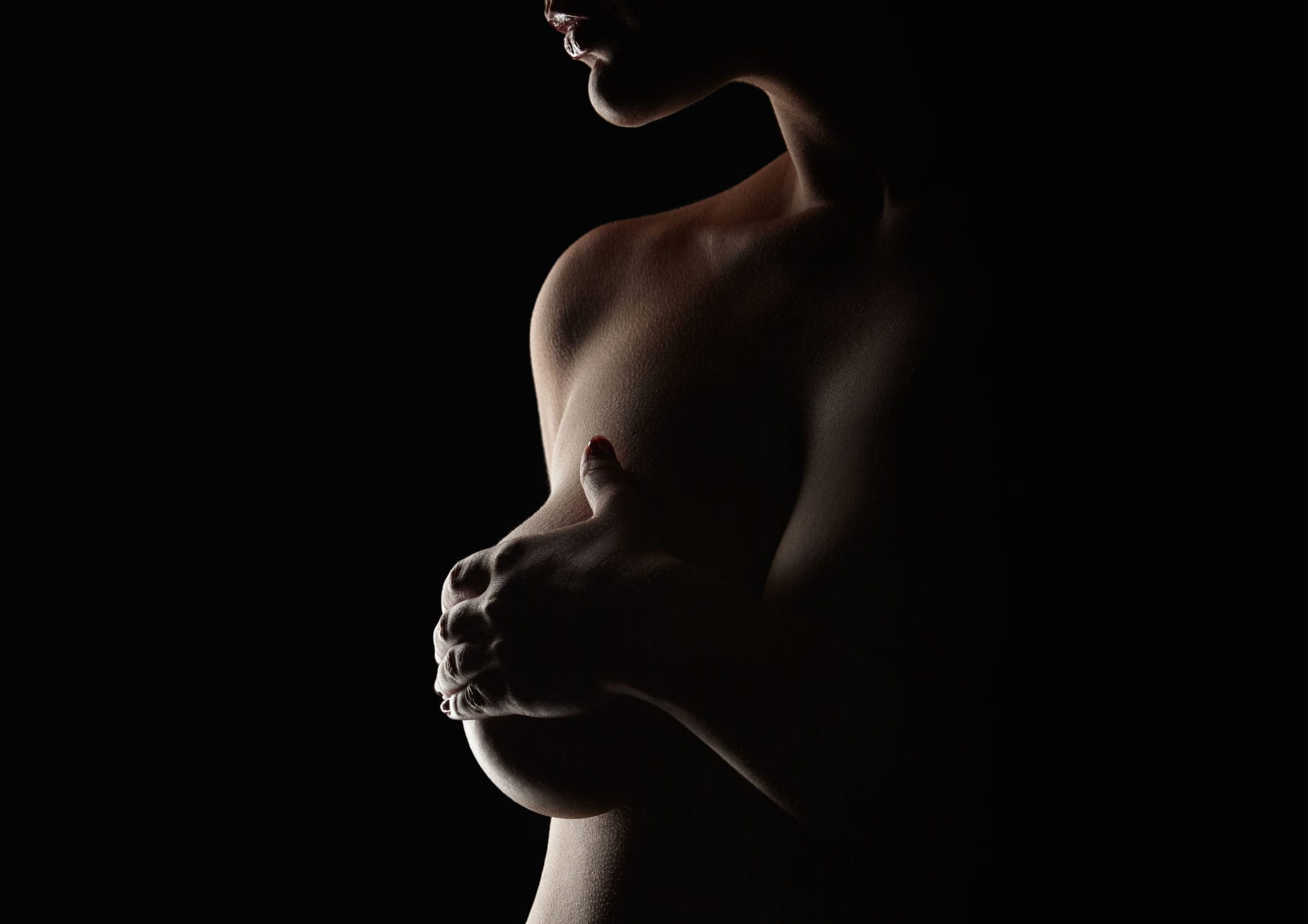Shadow lighting woman covering her breast in profile