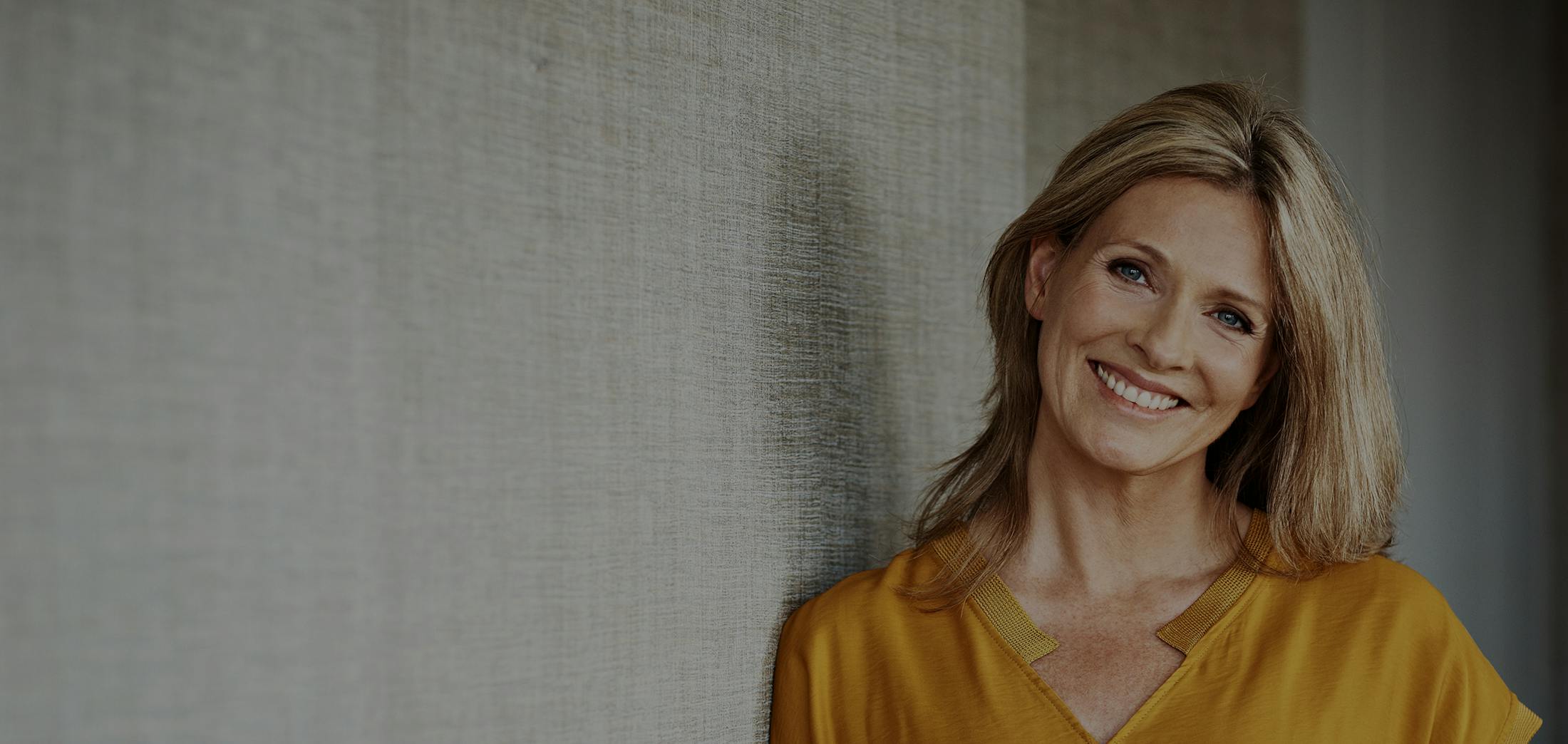 Older blonde woman smiling wearing yellow shirt
