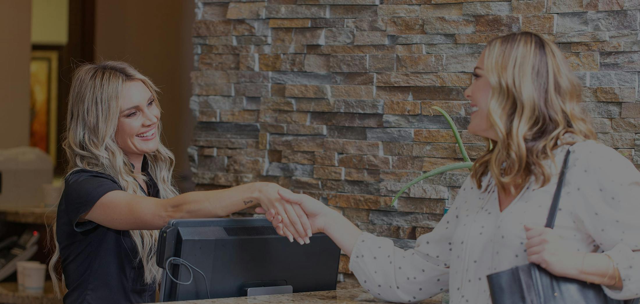 Female patient shaking front desk staff's hand