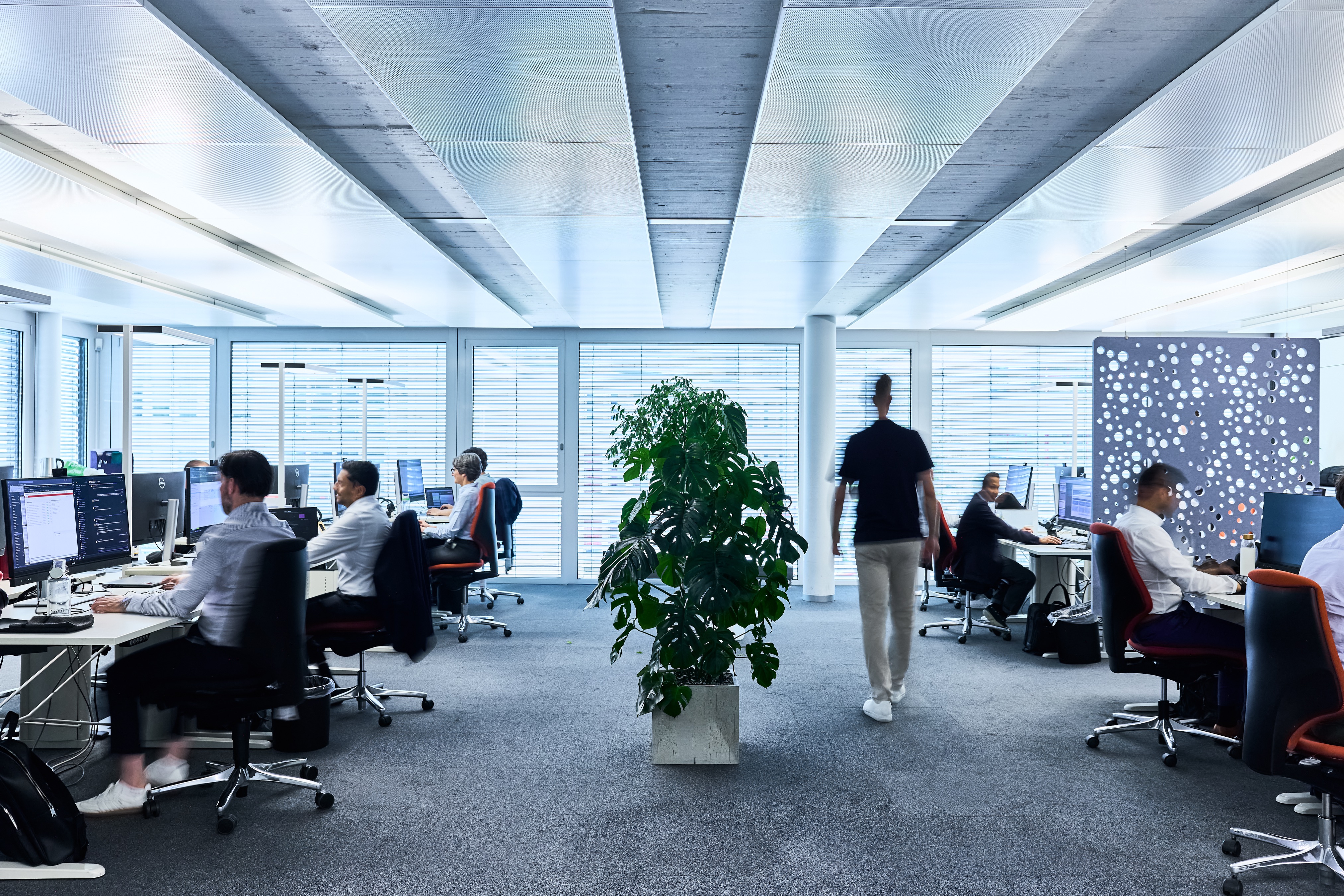Mitarbeiter, die an Schreibtischen in einem modernen Großraumbüro arbeiten.