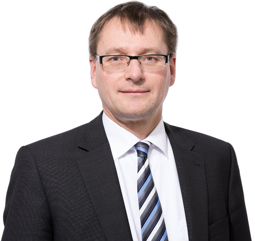 Ein Mann mittleren Alters im Anzug, mit weißem Hemd und gestreifter Krawatte, der eine Brille trägt.