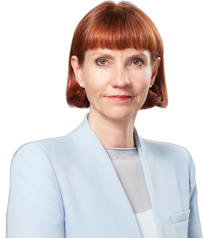 Ein professionelles Porträtfoto einer Frau mit schulterlangen rotbraunen Haaren, die einen hellblauen Blazer trägt.