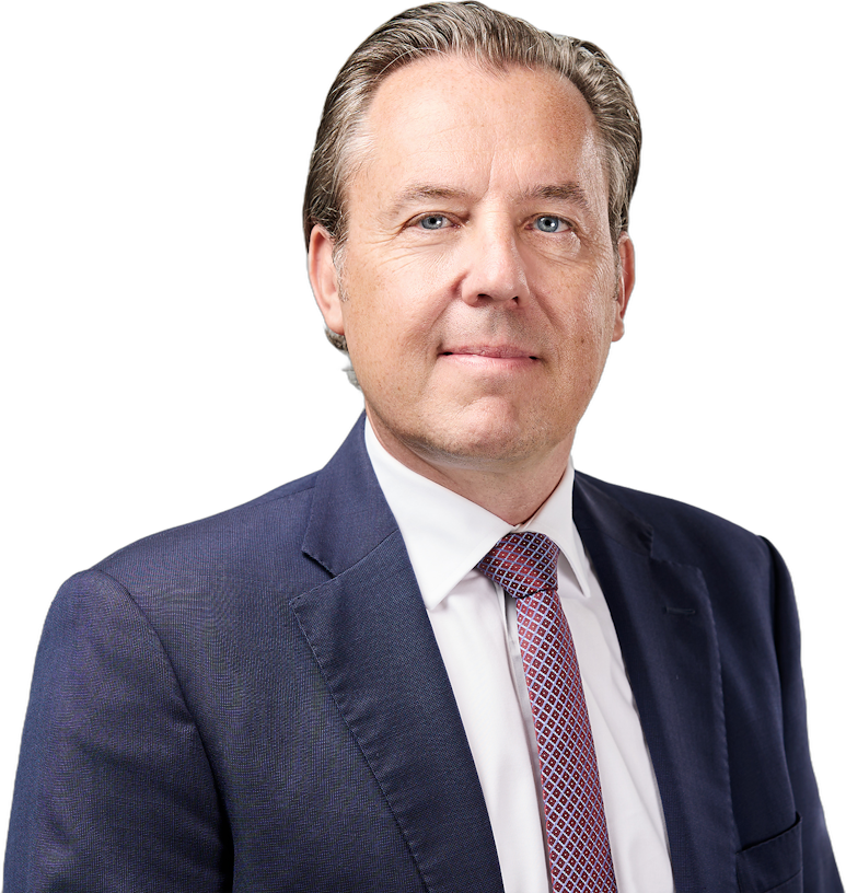Ein professionelles Porträtfoto eines Mannes mittleren Alters, der einen dunklen Anzug, ein weißes Hemd und eine gemusterte Krawatte trägt.