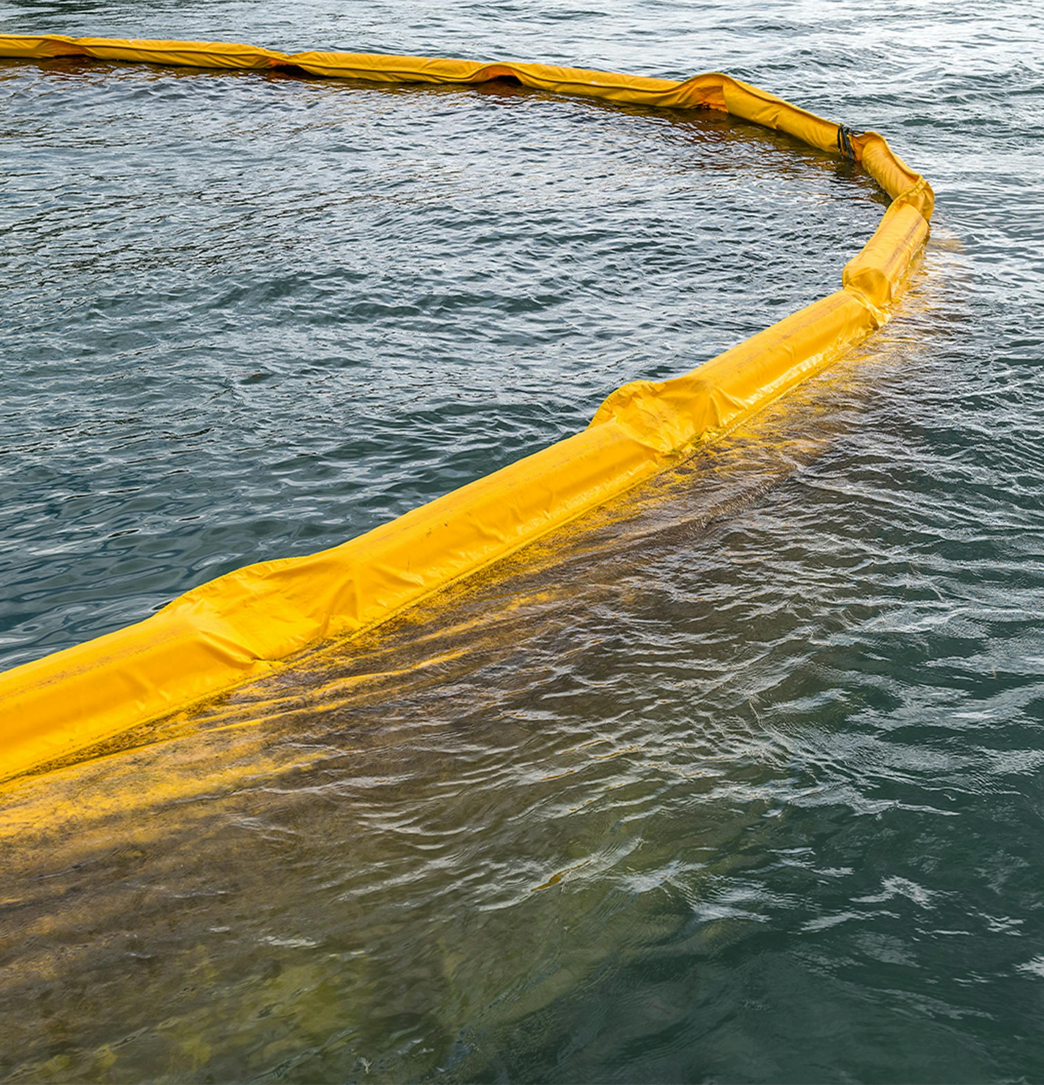 Yellow containment boom surrounding an oil spill on water