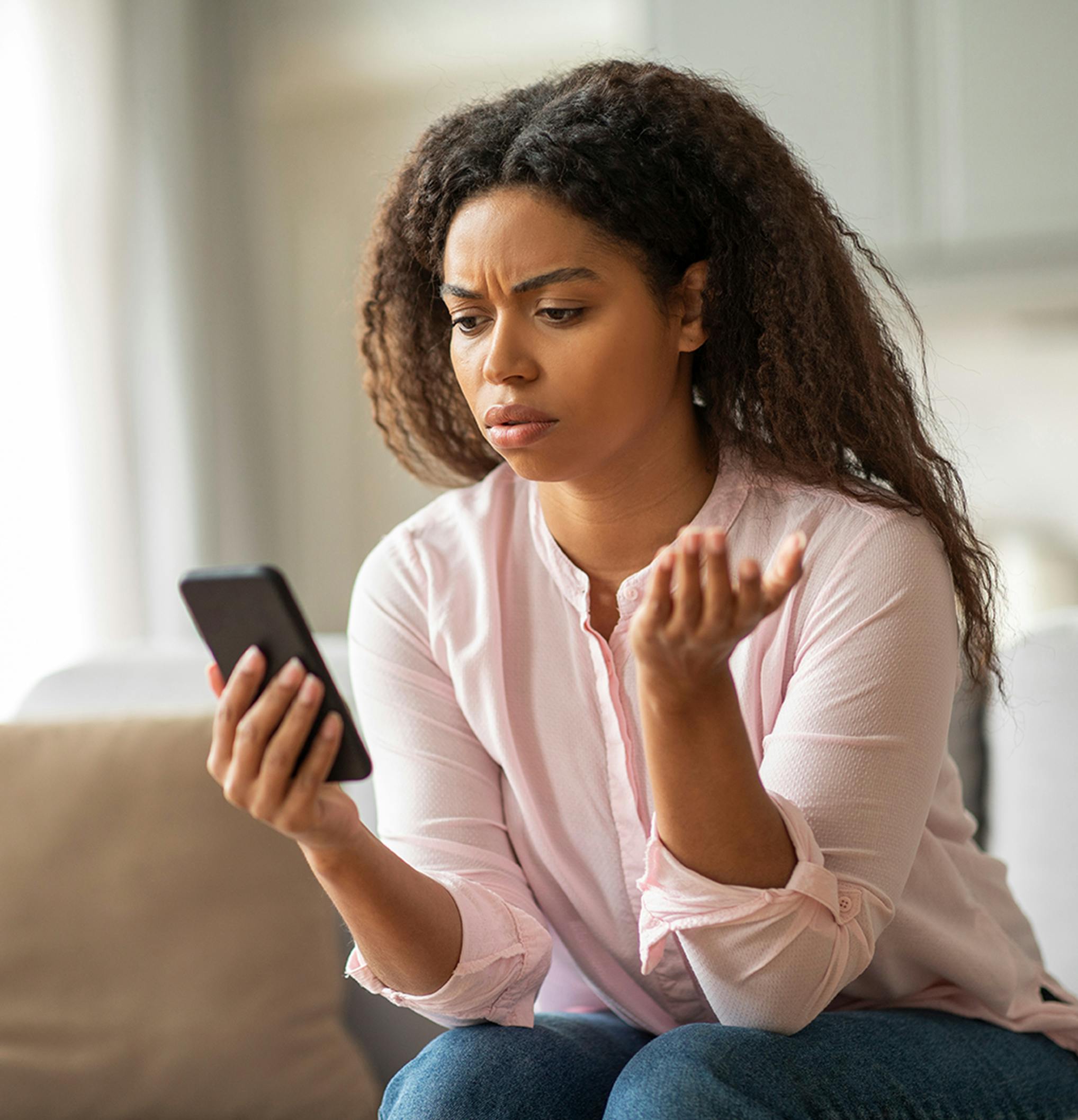 woman looking at her smart phone confused